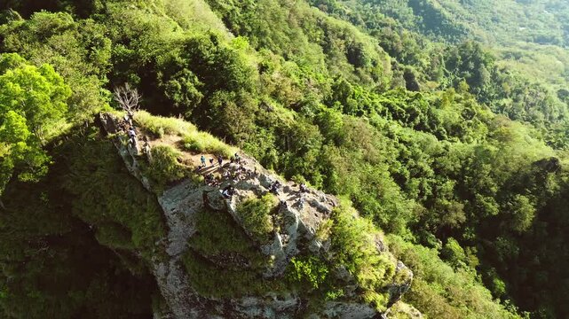An aerial view shows a group of climbers atop a high rock cliff, surrounded by lush tropical forest and a sweeping panorama of hills, in Sukoharjo, Central Java, Indonesia, on Sunday, June 8, 2025