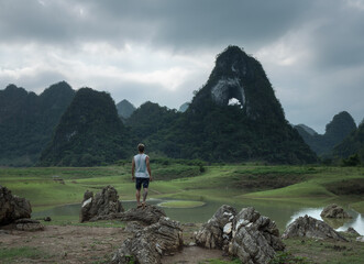 A solo male traveler at the scenic viewpoint on ''Angel's Eye' mountains in picturesque valley of Cao Bang province in northern Vietnam