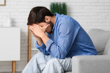 Fototapeta premium Tired young man sitting on couch at home