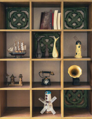 Neatly arranged decorative wooden shelf filled with vintage and eclectic objects including miniature model windmills, an antique rotary telephone, a gramophone and books