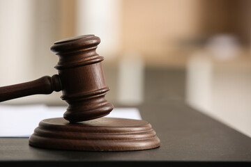 Judge's gavel with documents on black table in office, closeup
