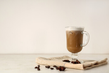 Glass cup of iced latte with star anise and coffee beans on white background