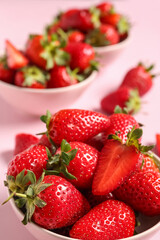 Bowls with sweet fresh strawberries on pink background, closeup