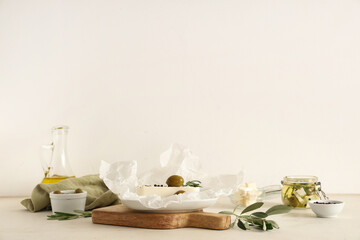 Paper with tasty feta cheese, olives, rosemary and peppercorn on white background