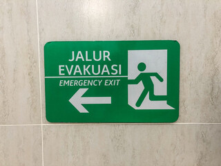 Evacuation route sign with white Wall background. The sign of the direction to the evacuation exit...
