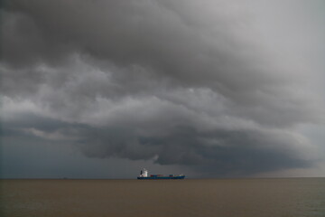 Cargo ship in Gulf of Thailand near Bangkok on October 30, 2020. Cloudy sky, calm sea, and container vessel suggest stormy weather.