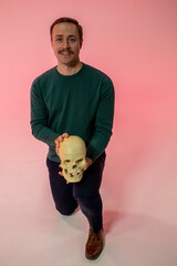 man with mustache holding a human skull