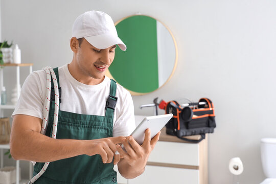 Male plumber using tablet computer in bathroom