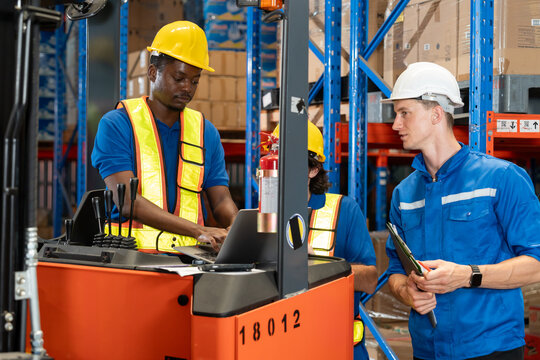 Multiracial warehouse team discussing logistics operations. Worker on forklift using laptop while supervisor holds clipboard. Concept of teamwork,supply chain tech, and real-time inventory monitoring.