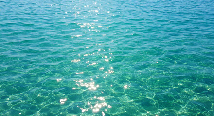 Obraz premium Sunlit turquoise water shimmers gently, reflecting light on its surface.