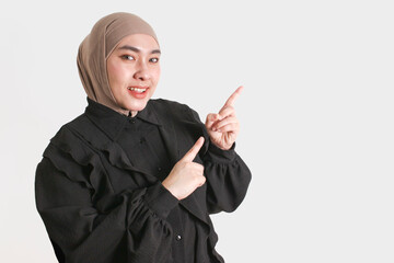 Confident Muslim woman in hijab and glasses with gesture pointing on isolated white background.