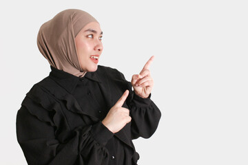 Confident Muslim woman in hijab and glasses with gesture pointing on isolated white background.