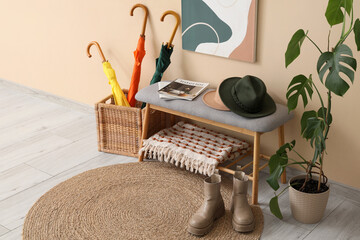 Wooden bench with cushion, hats and magazines in interior of hall, closeup
