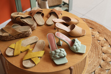 Stylish women's flip-flops on table in hallway, closeup