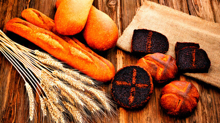 A variety of breads and pastries on an old wooden table, with wheat stalks in the background.