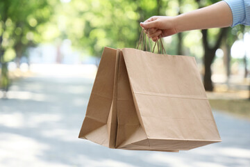 Female hand with paper bags outdoors. Food delivery service