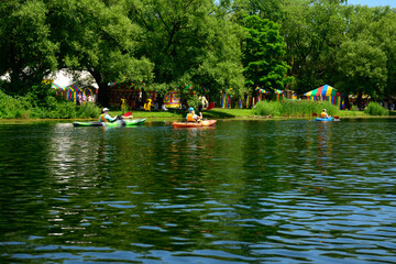 sea kayakers paddle past a cultural festival on toronto's centre island park on a sunny summer day...