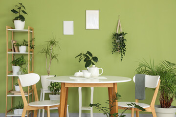 Interior of dining room with table, shelf unit and green plants