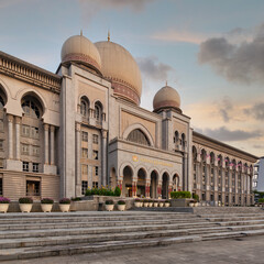 Obraz premium Istana Kehakiman, or Palace of Justice, in Putrajaya, Malaysia. Grand government building with prominent domes, arches, and intricate Islamic architecture under a soft evening sky