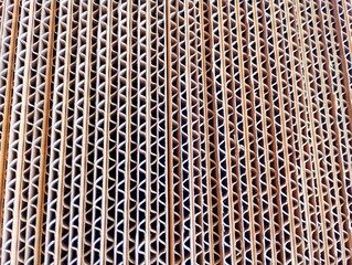 close-up view of stacked corrugated cardboard sheets, showing the corrugated grooved layers between...