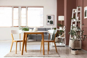 Interior of living room with green plants, sofa and dining table