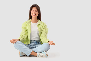Smiling young woman meditating on white background