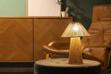 Glowing lamp on pouf in living room at night