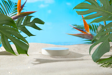 A centered white platform sits on soft tropical sand surrounded by overlapping monstera leaves and vibrant bird of paradise florals. Perfectly lit with summer sunlight, cosmetic product placement. © Tuan  Nguyen 