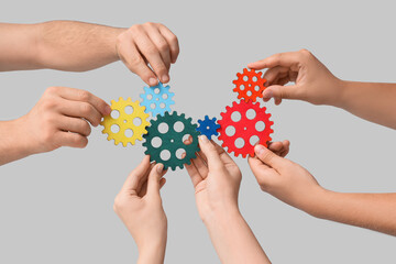 Many hands with colorful gears on light background