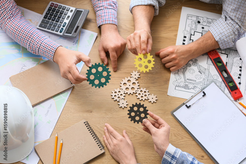 Poster hands of engineers with gears on table, top view