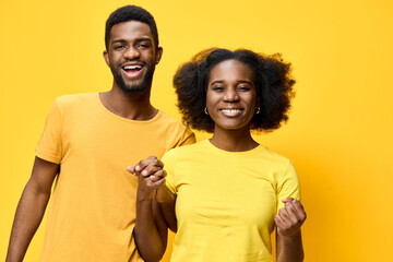 Happy African American couple wearing yellow shirts, expressing joy and positivity against a bright...