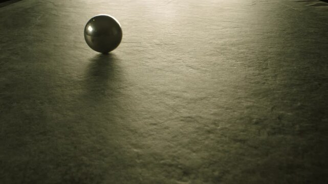 Three silicon nitride balls are rolling on the ceramic floor . Big medium and small heavy metallic or ceramic balls moving , knocking , hitting each other . Shot on ARRI ALEXA in Slow Motion