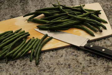 Trimming green beans on cutting board with kitchen knife