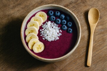 acai smoothie bowl with banana, coconut flakes and blueberries on wooden table in natural light, clean healthy breakfast concept of food blog, nutrition, wellness