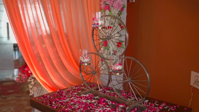 ornate bicycle wheel candle holder with rose petals, orange backdrop.