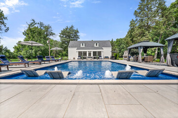Luxury pool house with water fountain feature and stunning setup under clear blue sky