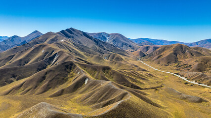 Aerial view of the alpine pass road winding its way through the arid mountain ranges at the Lindis...