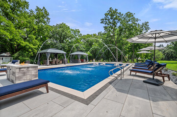 Luxury pool house with water fountain feature and stunning setup under clear blue sky