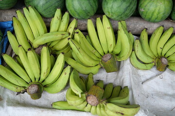 Five bunches of green bananas displayed at the seller's stall