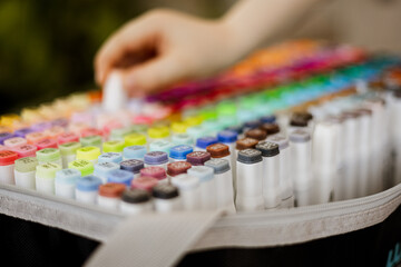 Hand picking colorful marker from art supply case, close-up view of alcohol-based markers