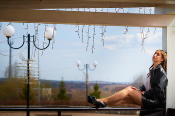 Model poses elegantly at outdoor location with decorative lights and scenic views on a sunny day