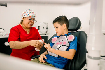 Latin american dentist teaching oral hygiene to boy