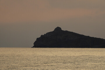 Sunset Seascape Mountain Silhouette Calm: Dramatic evening view with dark mountain against golden...