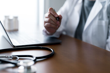 Doctor using laptop computer in medical office with stethoscope on desk, symbolizing healthcare IT systems, online consultation, digital tools for hospital workflow, and modern clinical management.