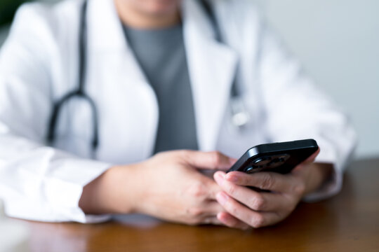 Close-up view of doctor using smartphone to access electronic health records, manage appointments, and communicate with patients, highlighting mobile integration in the healthcare system.