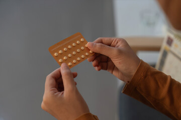 Medication Awareness. Individual examining birth control pill pack.