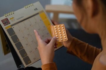 Health Routine. Woman checking calendar while managing medication schedule.