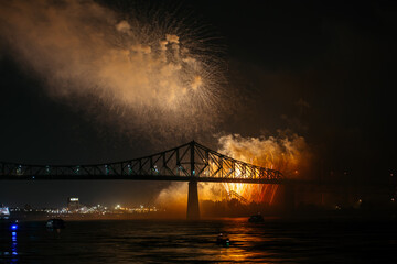 Drone flight through holiday fireworks above water with reflection on the black sky background