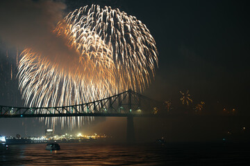 Drone flight through holiday fireworks above water with reflection on the black sky background