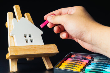A realistic White House model rests on a wooden easel, while an interior designer's hand delicately...